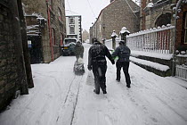 People carrying shopping along snow covered street, Denbigh, Denbighshire, Wales, January 2010