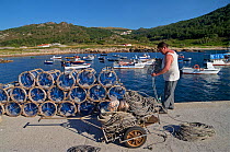 Man with octopus traps in the small harbour of Camelle, Galicia, Spain. July 2008.