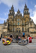 Bicycle pilgrims resting in front of Santiago de Compostela cathedral, after cycling the Camino de Santiago ("Way of St. James"). Galicia, Spain, July 2008.