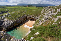 Secluded cove amongst karstic rocks on the Green Coast, Cantabria, Spain. Picos de Europa mountains in the distance. July 2008.