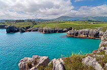 Turquoise water and karstic rocks on the Green Coast, Cantabria, Spain. Picos de Europa mountains in the distance. July 2008.