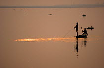 Silhouette of fisherman at sunset on the Dibru river, near Tinsukia, Assam, India March 2009