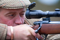 Deer stalker looking down telescopic sight of gun,  Glenfeshie, Cairngorms, Scotland, UK, June 2008, model released