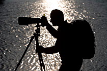 Photographer, Paul Chilton, silhouetted against Loch Garten, Scotland, October 2006