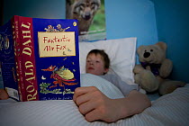 Boy reading 'Fantastic Mr Fox' book in bed, Scotland, UK, model released