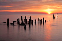 Baltic sea with posts sticking out of water at sunset, Latvia, June 2009