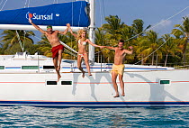 Three people jumping off a Sunsail Oceanis 423 in the BVI's, March 2006. Model and property released.