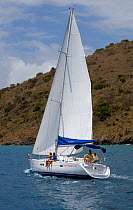 Sunsail Oceanis 423 sailing in the BVI, with couple sitting on the rail, March 2006. Model and property released.