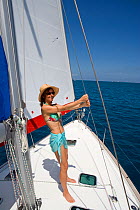 Woman holding onto mast stays aboard Sunsail Oceanis 423 in the BVI, March 2006. Model and property released.