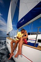 Couple relaxing on the rail of a Sunsail Oceanis 523 in the BVI, March 2006. Model and property released.