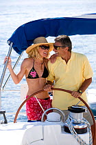 Couple helming a Sunsail Oceanis 523 in the BVI, March 2006. Model and property released.