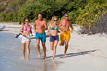 Friends running along a beach with a frisbee in the BVI, April 2006. Model released.