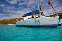 Man jumping off the bow of a Sunsail Lagoon 410 anchored in the BVI. April 2006, Model and property released.