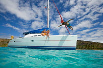 Man diving off the bow of a Sunsail Lagoon 410 anchored in the BVI. April 2006, Model and property released.