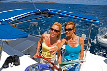 Women helming and navigating onboard a Sunsail Lagoon 410 in the BVI, April 2006. Model and property released.