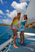 Women on the trampoline of a Sunsail Lagoon 410 in the BVI, April 2006. Model and property released.
