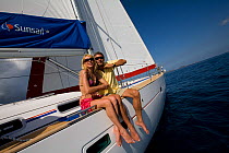 Couple relaxing on the rail of a Sunsail yacht in the British Virgin Islands, March 2006. Model and property released.