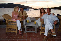 Two couples relaxing at a waterside bar in the British Virgin Islands, March 2006. Model released.