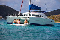 Friends in a tender beside a Sunsail catamaran moored in the British Virgin Islands, March 2006. Model and property released.