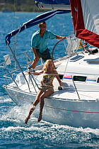 Woman dangling her legs over the side of a Sunsail yacht sailing in the British Virgin Islands, March 2006. Model and property released.