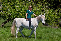 Woman riding Arabian Horse in field, bareback and guiding it only with neck loop, Northern California, USA (Model Released)