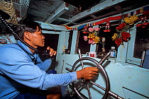 Captain at the helm of his fishing dragger boat, Sihanoukville, Kampuchea / Cambodia, June 2008