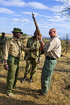 Security consultant (Ridgeback, Inc.) assisting in rifle cleaning and safety checks for Mara Conservancy rangers, Masai Mara Conservancy, Kenya, October 2006