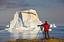 Photographer, Kai Jensen, on the coast near an iceberg, Qeqertarsuaq, Disko Bay, Greenland, August 2009