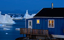 House on the coast with icebergs in the distance, Saqqaq, Greenland, August 2009