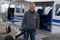 Photographer, Mark Carwardine, standing in front of plane used for aerial photography for Wild Wonders of Europe mission, Akureyri, Iceland, June 2009