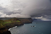 Coastline with wind turbines on cliffs just below dark clouds, Ponta de Sao Lourenco, Madeira, March 2009