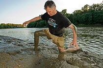 Photographer, Milan Radisics, in mud at the edge of the Tisza River, Hungary, June 2009