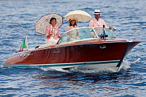 Classically dressed people with sunshades on Riva motorboat. Monaco Classic Week, September 2009.
