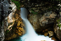 Waterfall coming through a hole in rock, River Moznica, Moznica valley, Triglav National Park, Slovenia, July 2009