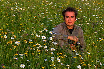 Photographer, Edwin Giesbers, in wild flower meadow during Wild Wonders of Europe mission, Liechtenstein, July 2009