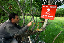 Person pointing at mine warning sign in a mine field near the village of Zadrzani, Northern Livanjsko Polje, an area affected by war (1991-1995) Bosnia and Herzegovina, May 2009