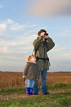 Mother and son bird watching on bird reserve at Cley, Norfolk, UK, January 2008, model released