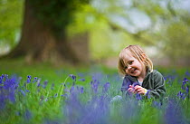 Child playing amongst Bluebells, Norfolk, UK, May, model released