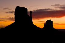 West and East Mitten buttes silhouetted at sunset, Monument Valley, Navajo Tribal Park, Arizona, USA. February 2009.