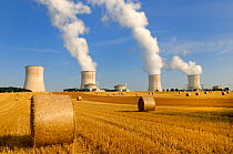 Cooling towers of Nuclear power station with farmland and straw bales in the foreground, Cattenom, France