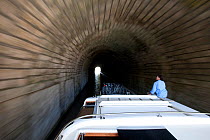 Woman on boat passing through a tunnel on the Canal Du Midi near Capestang, Languedoc, France. July 2009. Model and property released.
