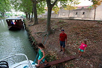 Girls walking onto a boat, Canal Du Midi near Capestang, Languedoc, France. July 2009. Model and property released.