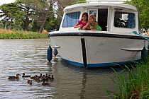 Girls feeding mallard ducks from a boat cruising on the Canal Du Midi near Capestang, Languedoc, France. July 2009. Model and property released.