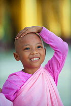 Portrait of a young Buddhist girl nun wearing pink robes in Bago, Myanmar / Burma.  August 2009