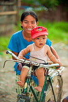 Portrait  of a little boy sat on the handlebars of a bicycle, in Inle Lake area, Shan State, Myanmar, Burma  August 2009