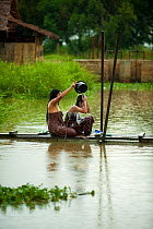 Women washing outdoors during rains, Inle Lake, Shan State, Myanmar, Burma. August 2009