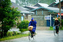 Cyclists in heavy rain, Nyaungshwe, Shan State, Myanmar, Burma August 2009