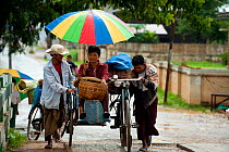 People cycling in the rain, Nyaungshwe, Shan State, Myanmar, Burma. August 2009