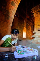 Woman painting souvenirs to sell to tourists at a temple in Old Bagan, UNESCO World Heritage, Mandalay State, Myanmar, Burma. September 2009