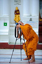Buddhist monk taking photos in Shwedagon Paya, the most important buddhist place in all Myanmar, Yangon, Rangun, Myanmar, Burma. September 2009
